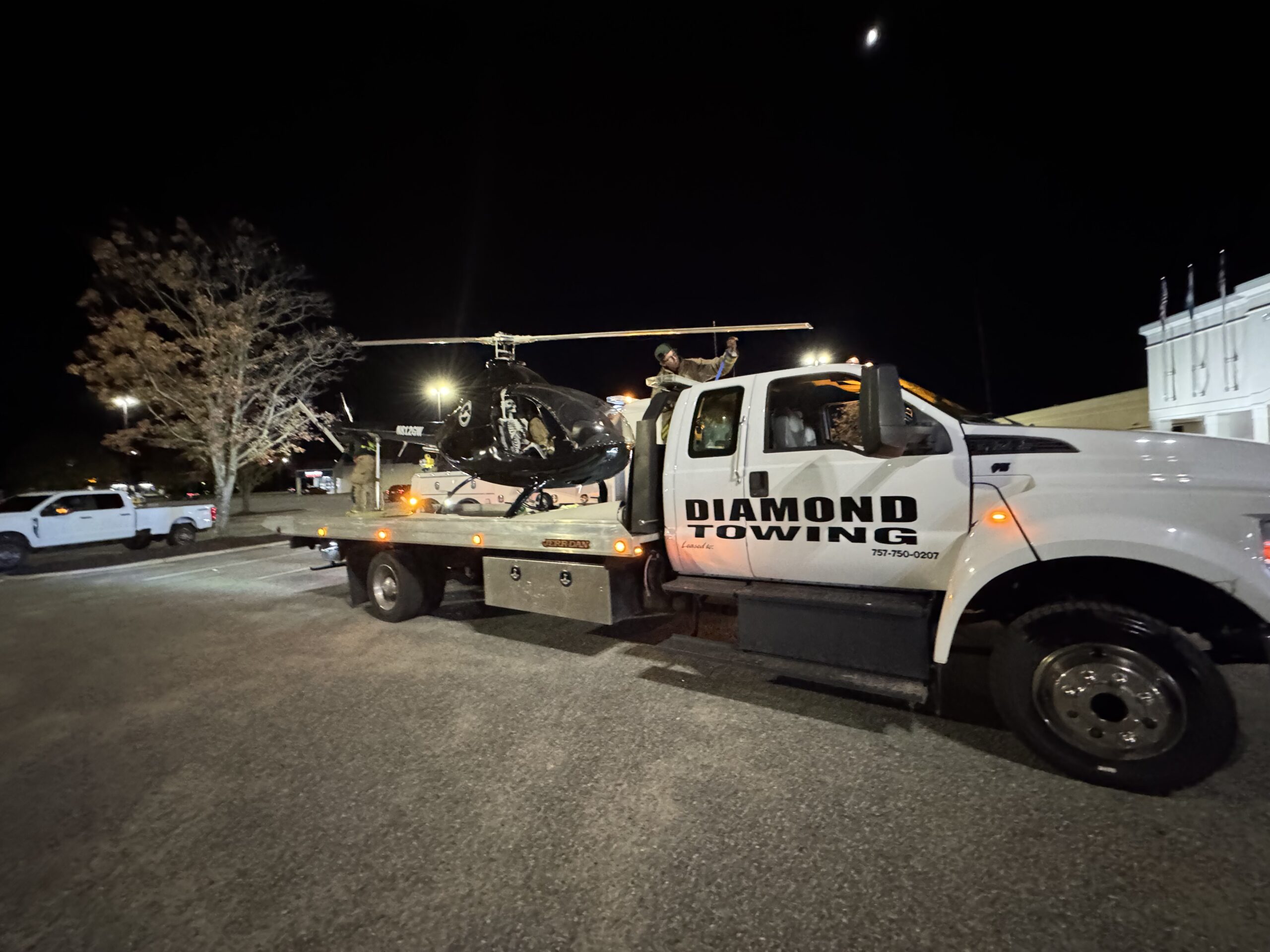 Diamond Towing flatbed transporting a military helicopter at night