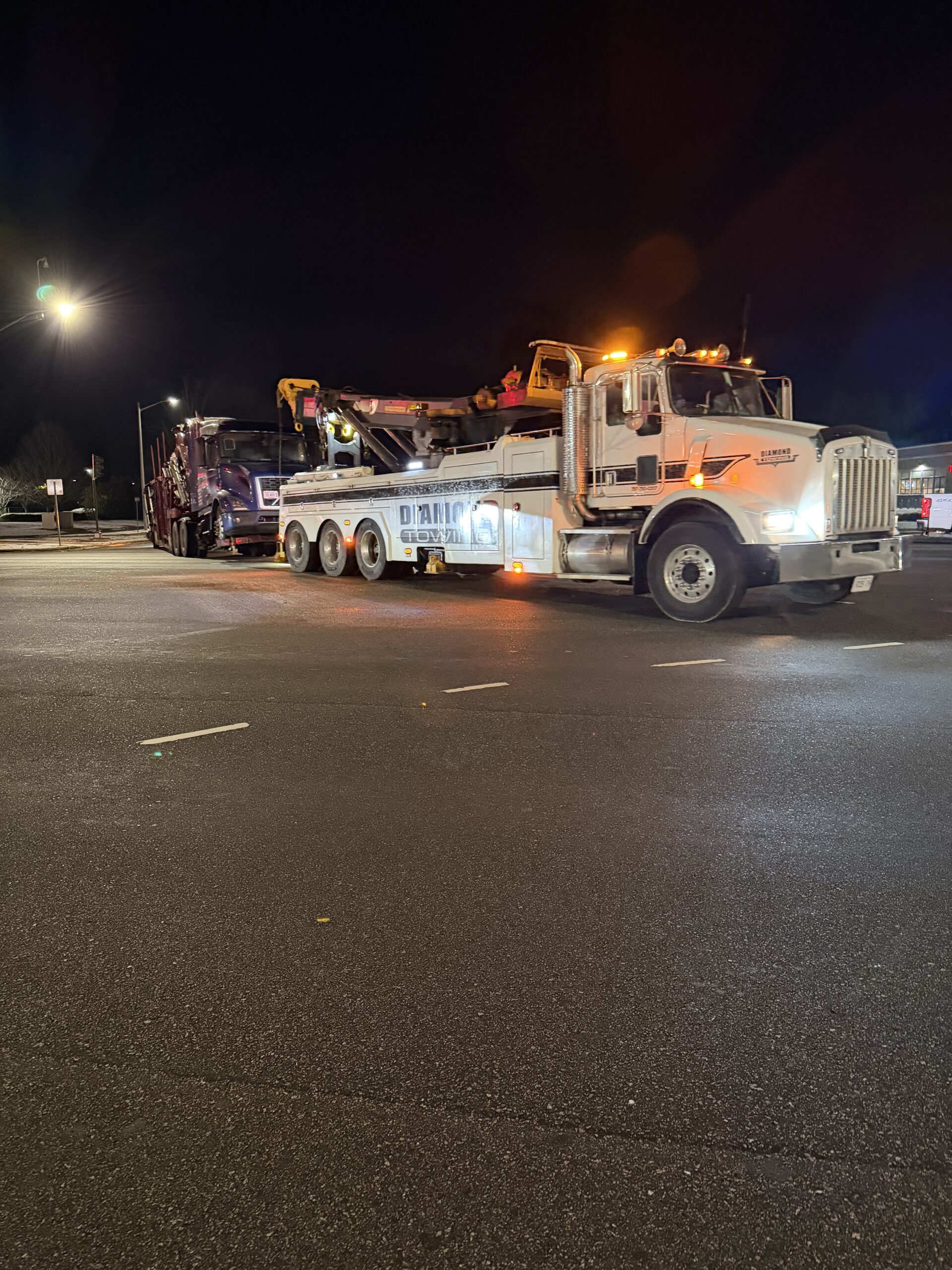 Diamond Towing Peterbilt heavy-duty wrecker towing a tractor-trailer at night